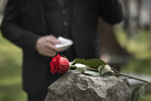 man paying respect tombstone cemetery