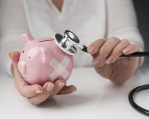 person putting stethoscope piggy bank