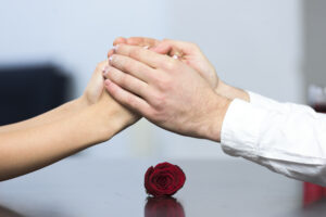 young couple table with rose holding hands