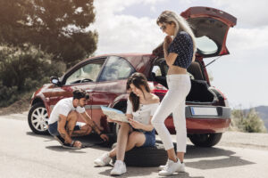 female looking map near man examining broken down car